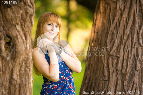 Image of Happy young beautiful girl standing between two trees