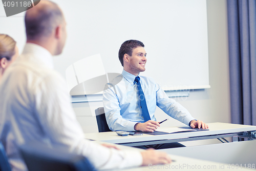 Image of group of smiling businesspeople meeting in office