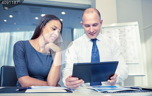 Image of smiling businesspeople with tablet pc in office