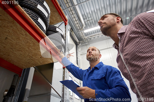 Image of auto mechanic and man with tires at car shop