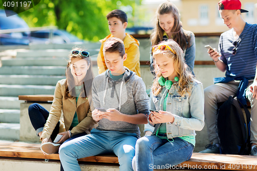 Image of happy teenage friends with smartphones outdoors