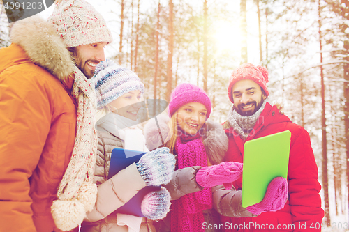 Image of smiling friends with tablet pc in winter forest