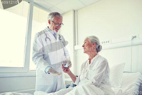 Image of doctor giving medicine to senior woman at hospital