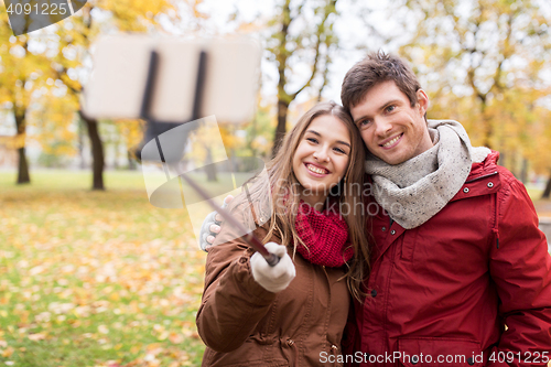 Image of couple taking selfie by smartphone in autumn park