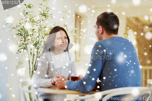 Image of happy couple with tea holding hands at restaurant