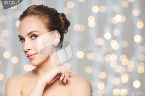 Image of beautiful young woman face over holidays lights