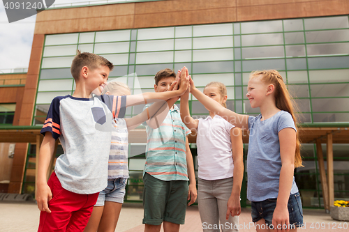 Image of group of children making high five at school yard