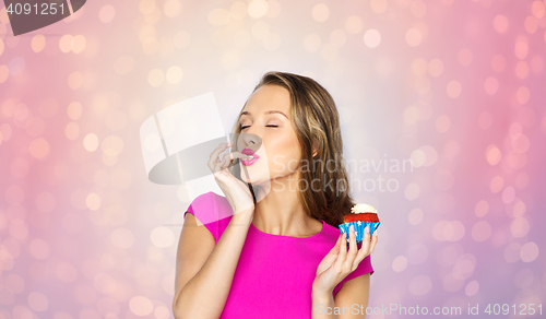 Image of happy young woman eating birthday cupcake