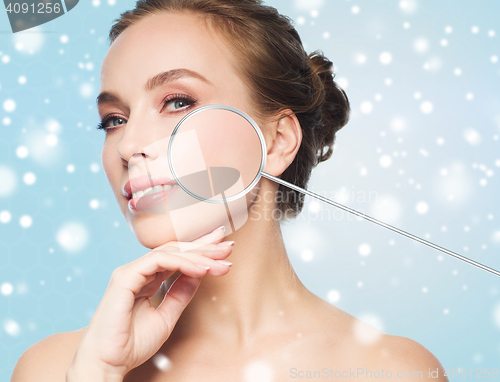 Image of beautiful woman with magnifier on face over snow