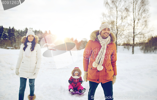 Image of happy family with sled walking in winter outdoors