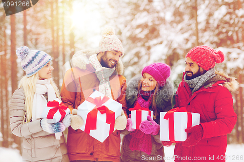 Image of happy friends with gift boxes in winter forest