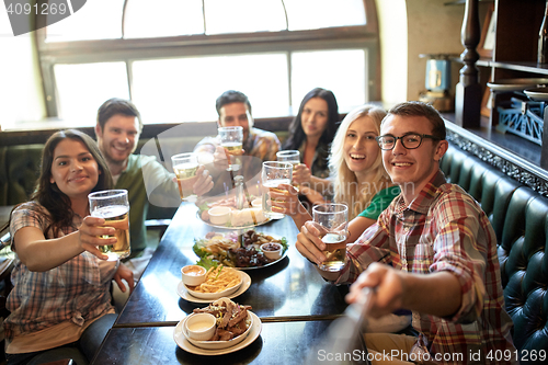 Image of happy friends with selfie stick at bar or pub