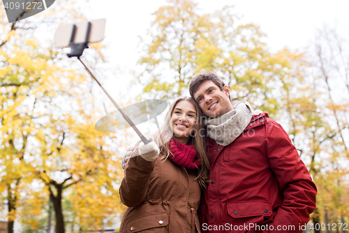 Image of couple taking selfie by smartphone in autumn park