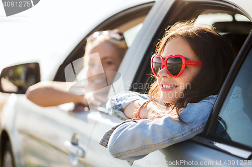 Image of happy teenage girls or women in car at seaside