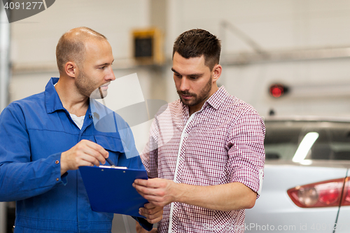 Image of auto mechanic with clipboard and man at car shop