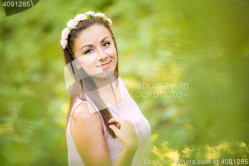 Image of Portrait of a young beautiful girl on a blurred background of green foliage