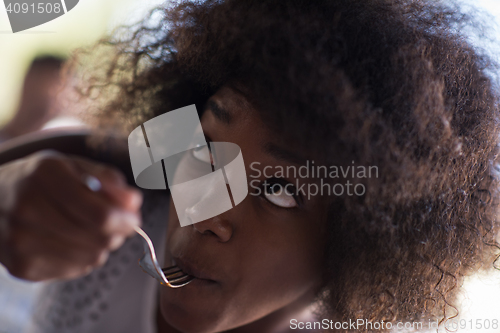 Image of a young African American woman eating pasta