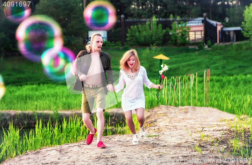 Image of Young Couple Running On The Grass