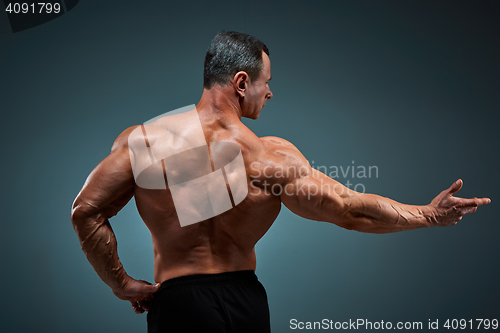 Image of torso of attractive male body builder on gray background.