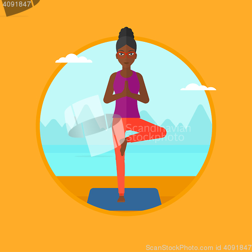 Image of Woman practicing yoga tree pose on the beach.