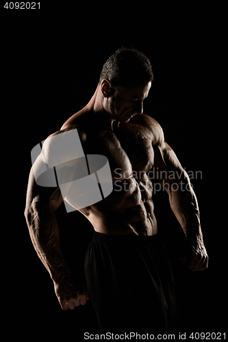 Image of torso of attractive male body builder on black background.