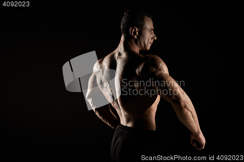 Image of torso of attractive male body builder on black background.