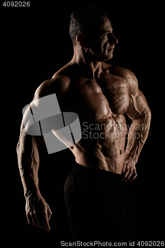 Image of torso of attractive male body builder on black background.