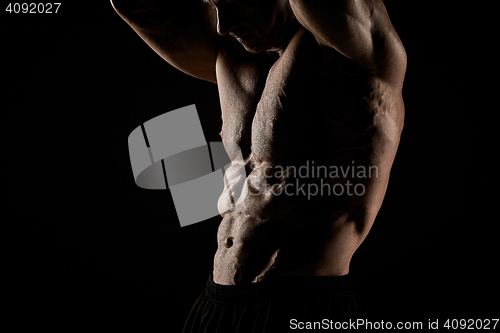 Image of torso of attractive male body builder on black background.