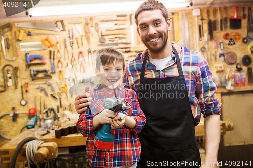 Image of father and son with drill working at workshop