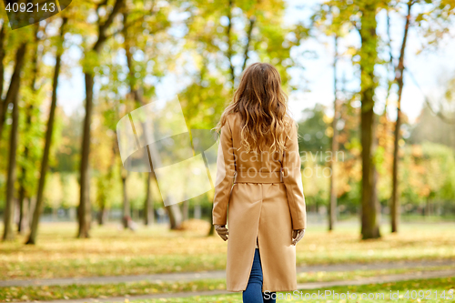 Image of beautiful young woman walking in autumn park