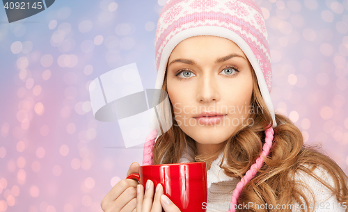 Image of happy young woman in winter hat with cup of tea