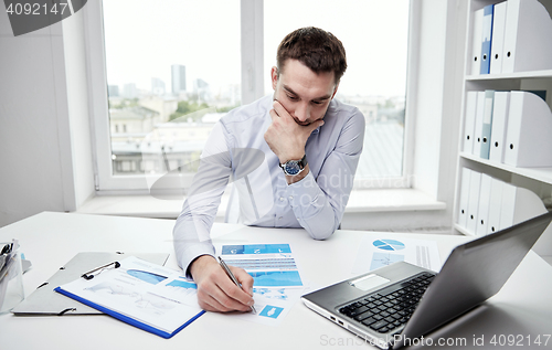 Image of stressed businessman with papers in office