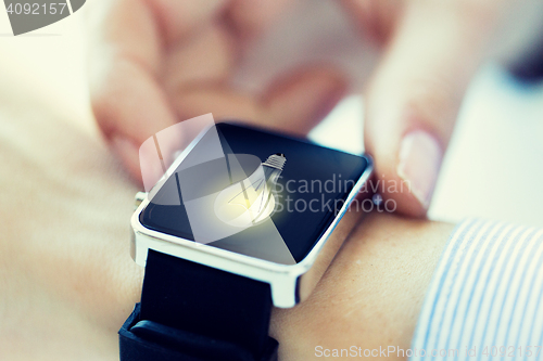 Image of close up of hands with lightbulb on smartwatch