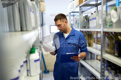 Image of auto mechanic with oil and clipboard at car shop