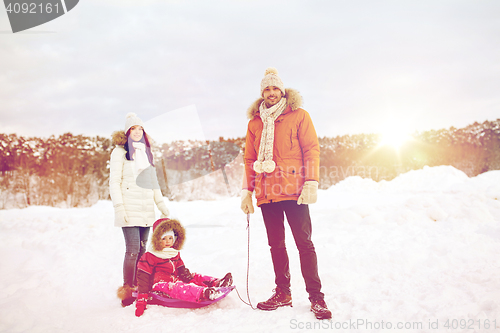 Image of happy family with sled walking in winter outdoors