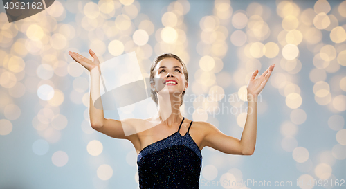 Image of smiling woman raising hands and looking up