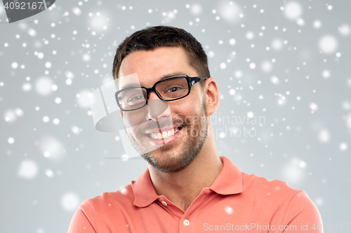 Image of happy smiling man in eyeglasses over snow