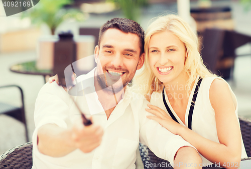 Image of happy couple taking selfie with smartphone at cafe