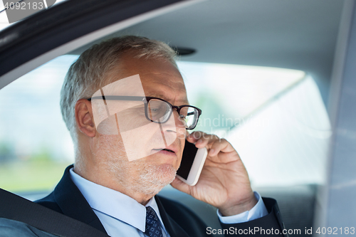 Image of senior businessman calling on smartphone in car