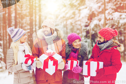 Image of happy friends with gift boxes in winter forest