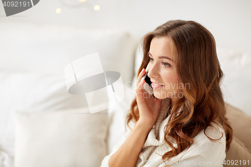 Image of happy young woman calling on smartphone at home