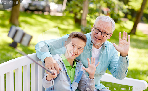 Image of old man and boy taking selfie by smartphone