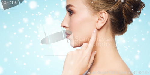 Image of close up of woman pointing finger to ear over snow