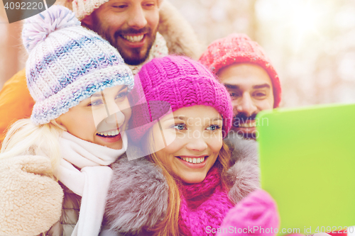 Image of smiling friends with tablet pc in winter forest