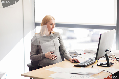 Image of pregnant businesswoman with computer at office