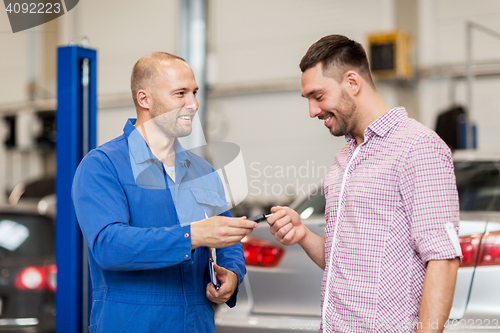 Image of auto mechanic giving key to man at car shop