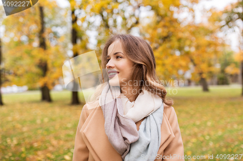 Image of beautiful happy young woman smiling in autumn park