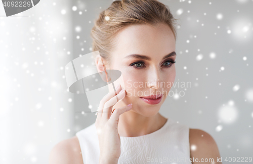 Image of close up of woman in white touching her face