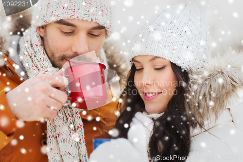 Image of happy couple with tea cups over winter landscape