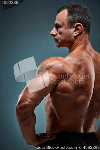 Image of torso of attractive male body builder on gray background.